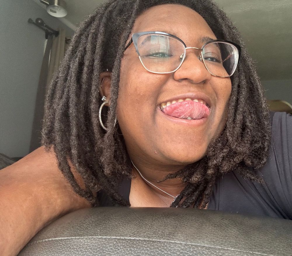 Op smiling against the sunlight, lifting her tongue up and leaning over her couch