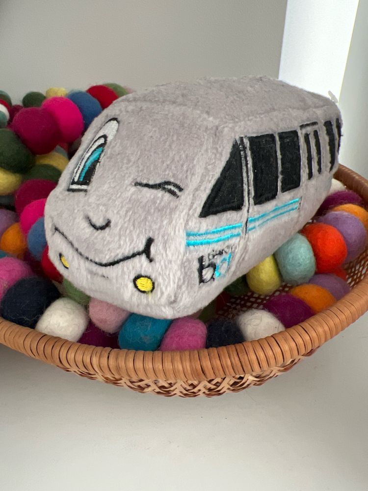 Legacy BART plushie with a winking face imposed on the front of the plushie train car.