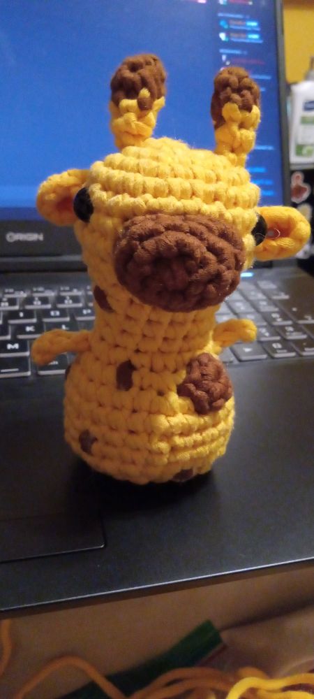 The front view of a yellow and brown crocheted giraffe 