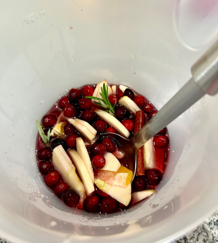 Bright red Sangria with fresh fruit, rosemary, and cinnamon sticks. 
