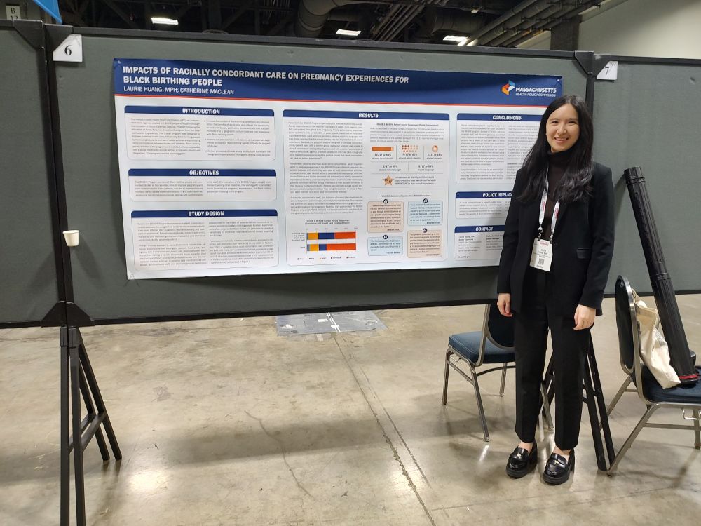 A photo of one HPC investment program staff member standing in front of HPC's “Impacts of Racially Concordant Care on Pregnancy Experiences for Black Birthing People”. 