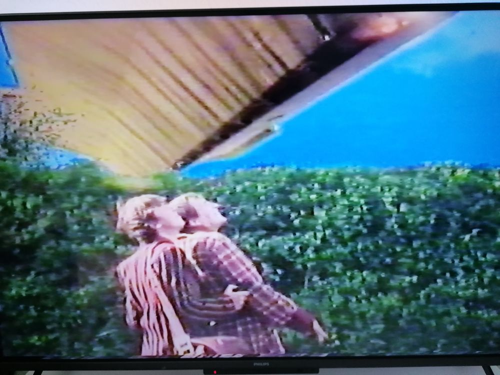 Screenshot aus "Per Anhalter durch die Galaxis".
Arthur Dent und Ford Prefect sehen zu einem Schiff der vogonischen Bauflotte hoch, das über ihnen am Himmel schwebt. 