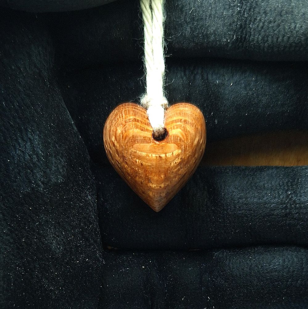 A heart pendant made from Northern Silky Oak. It dangles from cotton yarn.