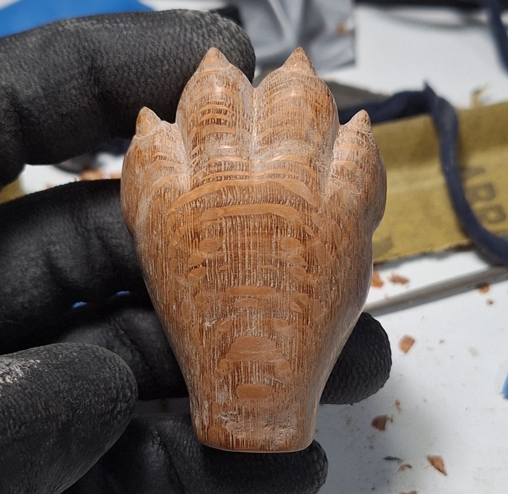A woodcarved paw held by a gloved hand.