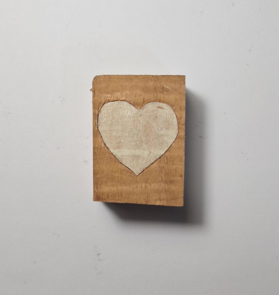 A heart drawn on a block of wood. Do not let the lack of reference size fool you, it is only 4x3cm