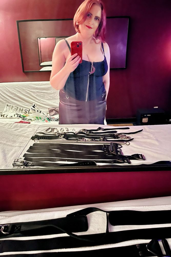 Scarlet mirror selfie with various bondage straps in foreground 