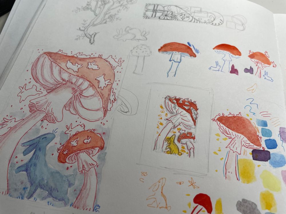 Sketchbook page exploring variations of a possible painting. The painting is of a rabbit looking at large amanita mushrooms. The white spots of the mushrooms are small white rabbits. 