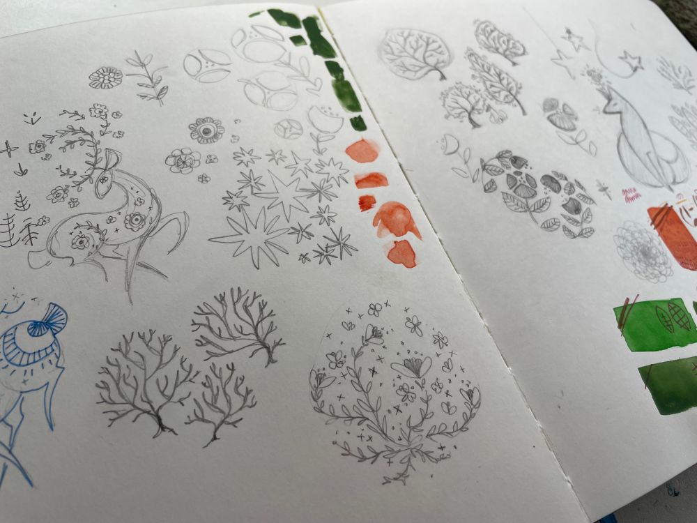 A sketchbook spread filled with smaller doodles of trees, plants, and stylized animals.  Some splashes of red and green watercolor have been tested on this spread.   