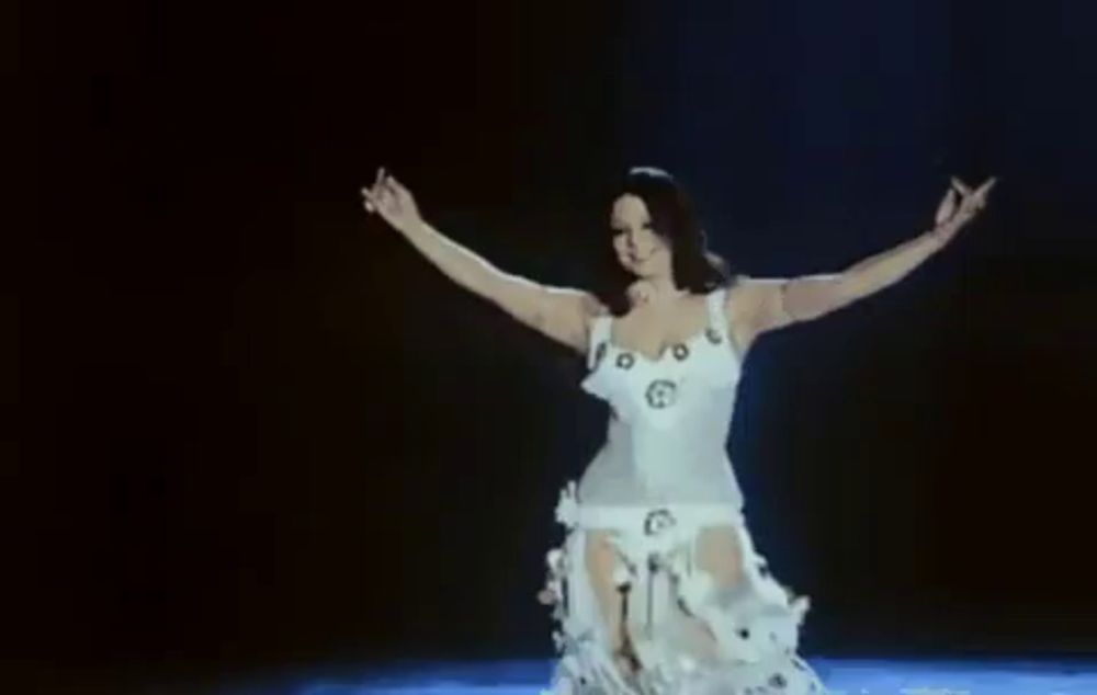 a woman in a white dress is dancing underwater in the dark .