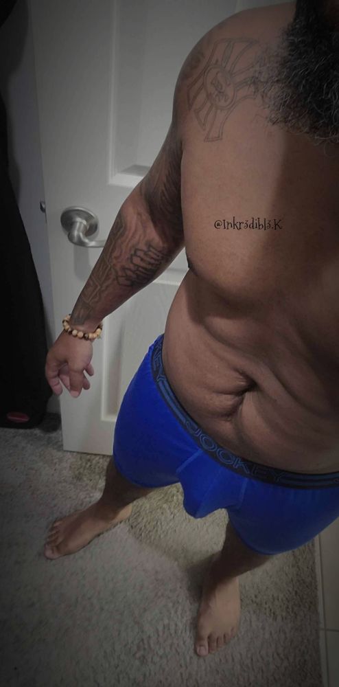 A side/front view of my body showing my stomach, chest, and bulge showing through my blue briefs 