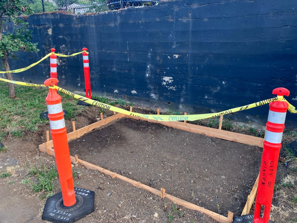 A foundation in progress framed by what I assume are two by fours. They are surrounded with orange traffic flex posts and caution tape. Since this is right next to one of the saddest bus stops ever, I am pretty sure this is the early stages of a new and much improved stop.