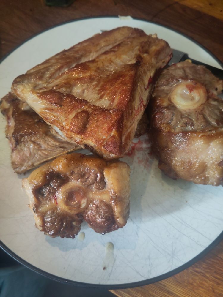 Two oxtails and two half racks of poem ribs that been well browned 