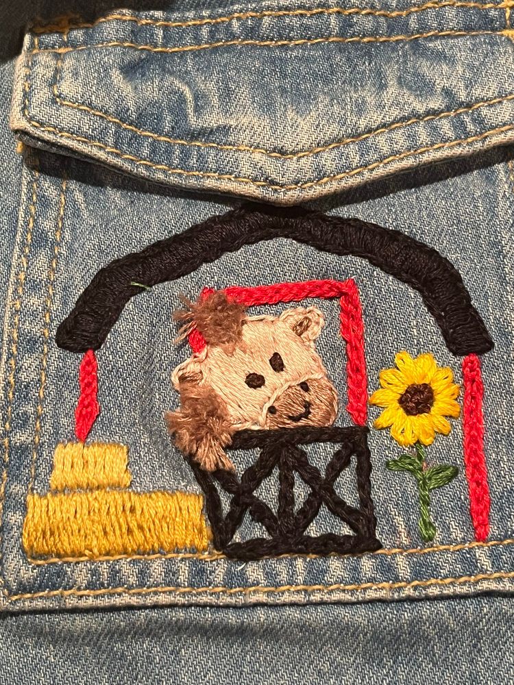A close up of the right pocket. A red barn with a horse and a sunflower. 