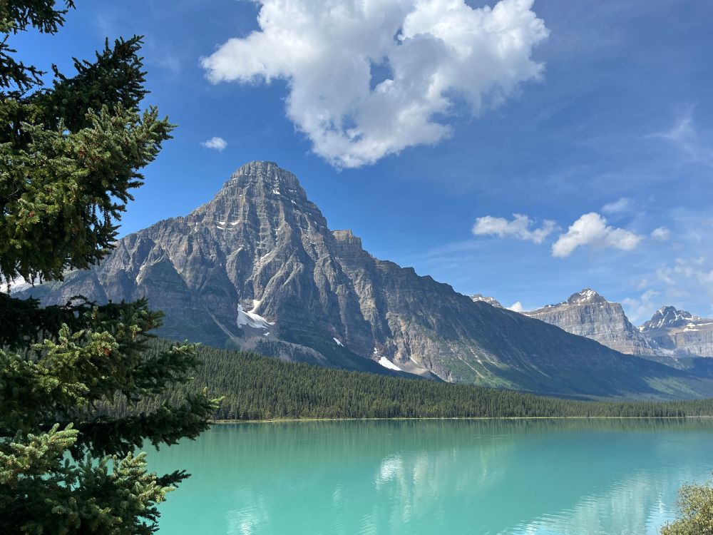 A landscape view of a Canadian mountain with a teal green lake in the foreground. 