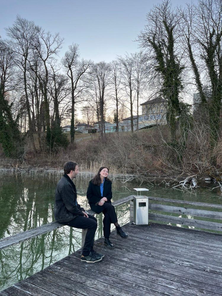 Two participants exchanging ideas during a lakeside peer-to-peer session