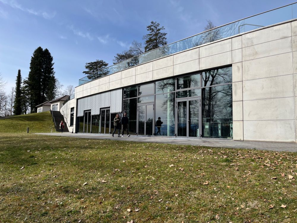 Workshop participants walking outside the auditorium of APB Tutzing on a sunny day.