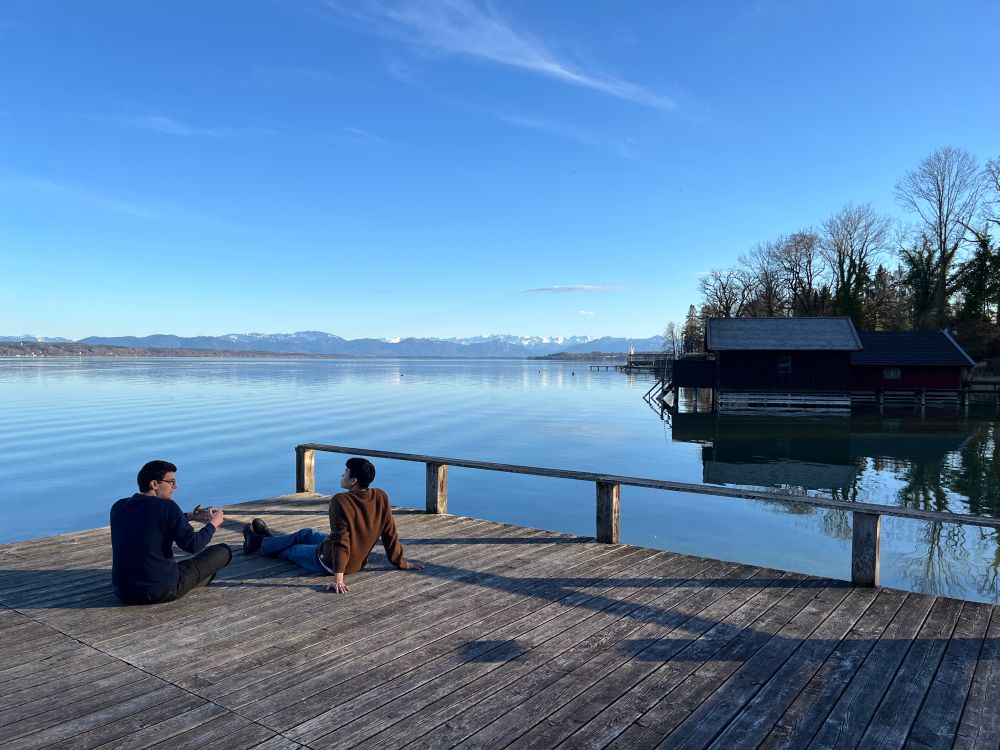 Starnberger See shows its beauty, with workshop participants sitting on the pier.