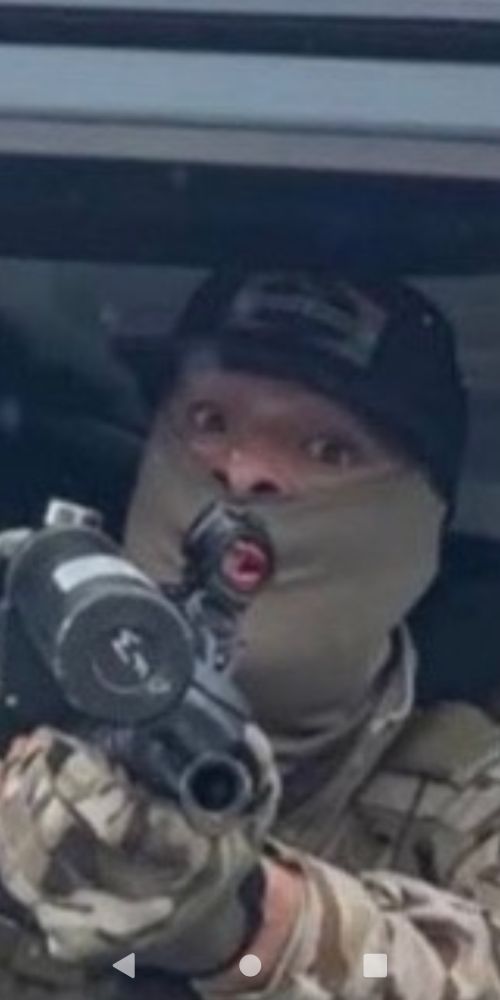 A scared tactical dude pointing a gun at the camera. 
It looks like he has a little butthole mouth all squunched up, making the frightened expression in his eyes look even sillier.
He is risible and we should mock him, but also he is dangerous because he is empowered by the state to enact violence on its citizens and visitors. 
