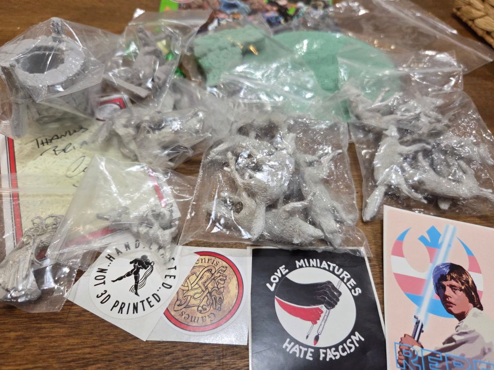 A varied bunch of pewter and resin miniatures in little zip lock baggies, and some stickers including the excellent troll-bait Love Miniatures Hate Fascism sticker.