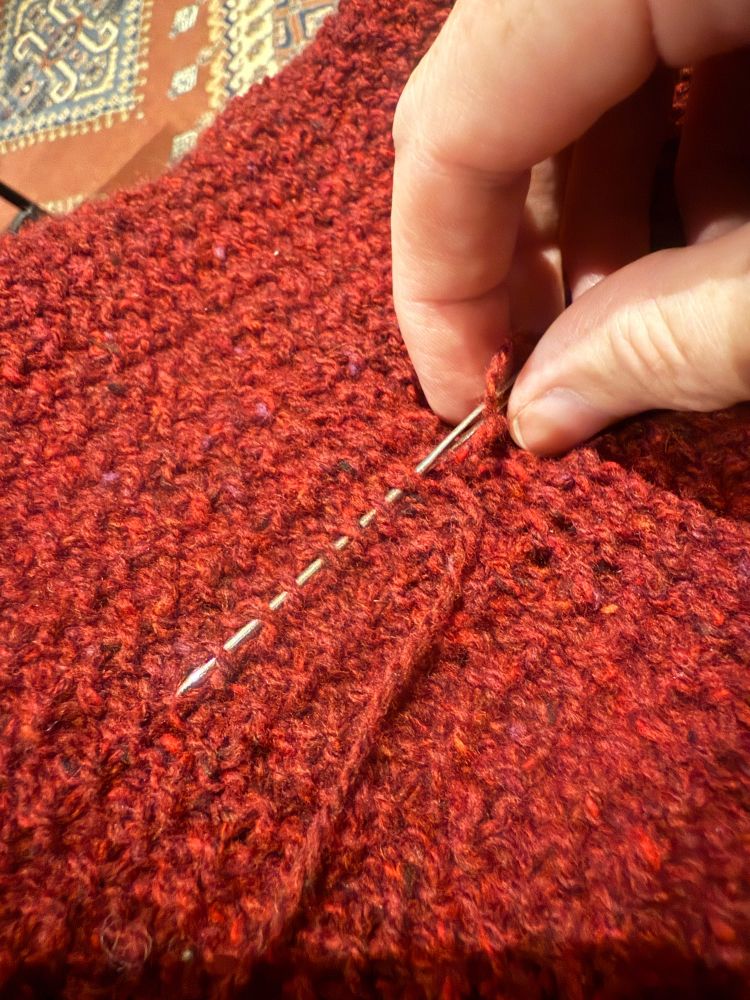 Me, carefully weaving in the ends of yarn that are hanging loose from the jumper I’m almost done with. 