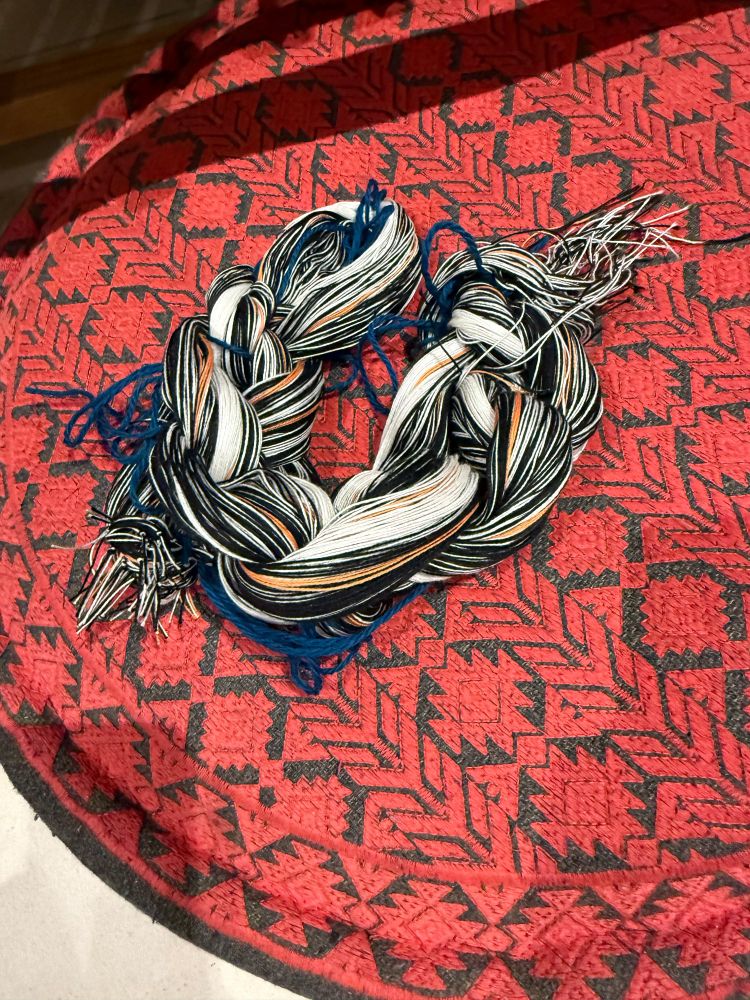 A mostly black and white braid of cotton yarns with small stripes of pale orange sitting on a cushion for me to photograph. Nothing exciting happening here. 