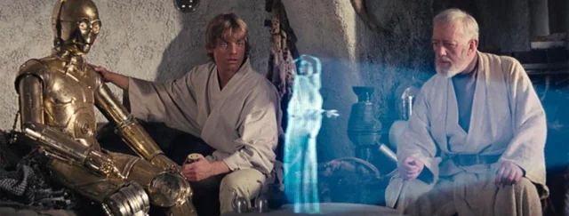 Luke, Obi-wan, and C-3PO look on as R2-D2 (out of view) plays a hologram of Princess Leia asking for Obi-wan's help.