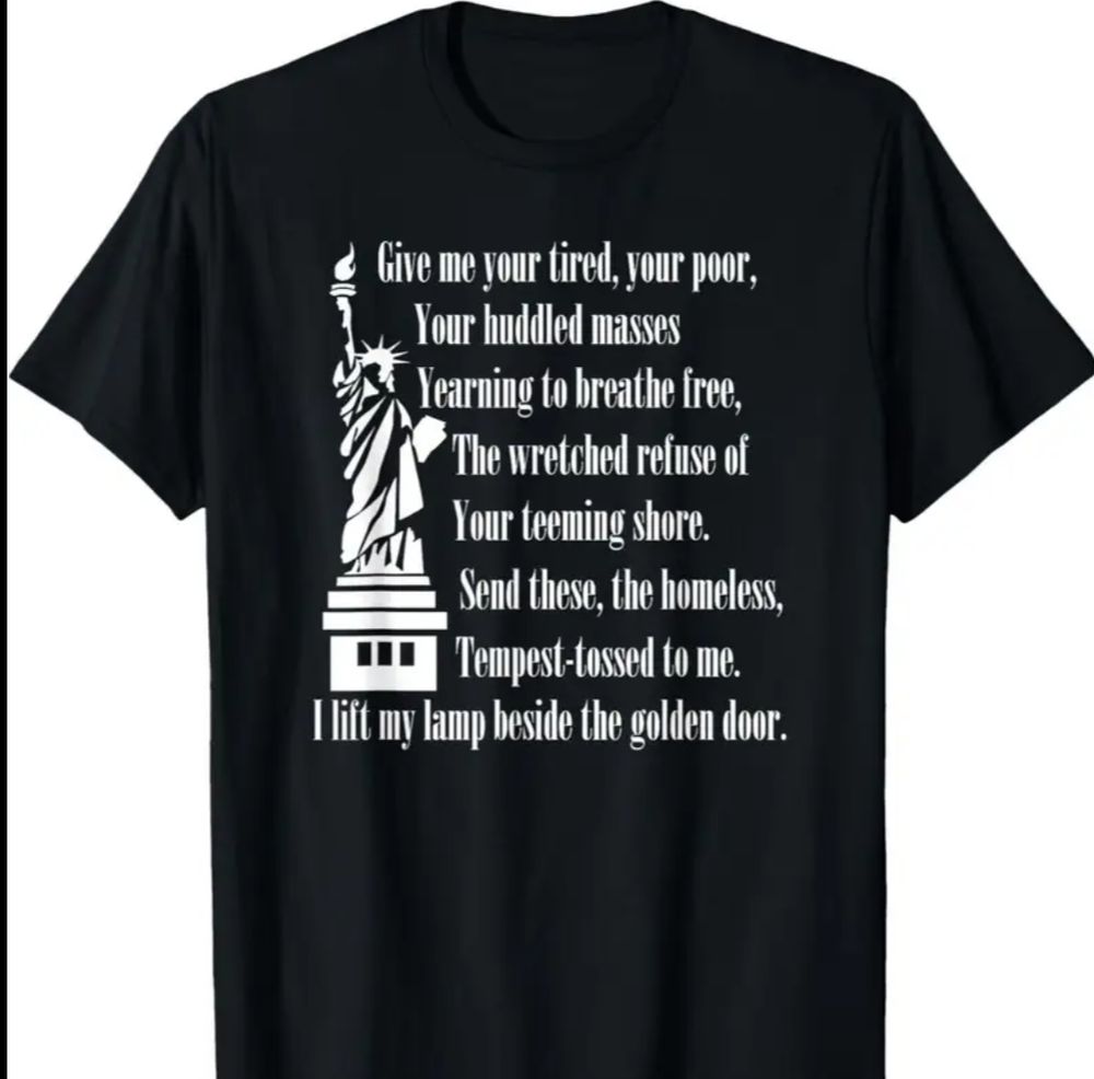 Black tee with white graphic and lettering. To the left side an image of the Statue of Liberty. Alongside that on the right, part of the poem by Emma Lazarus:
"Give me your tired, your poor, your huddled masses yearning to breathe free, the wretched refuse of your teeming shore. Send these, the homeless, the tempest-tossed to me. I lift my lamp beside the golden door."