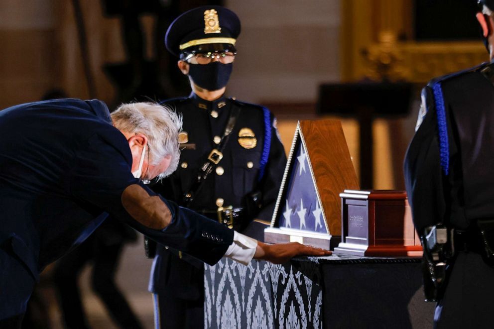 Memorial of Officer Sicknick, a mourner in front of his flag and cremated remains. 