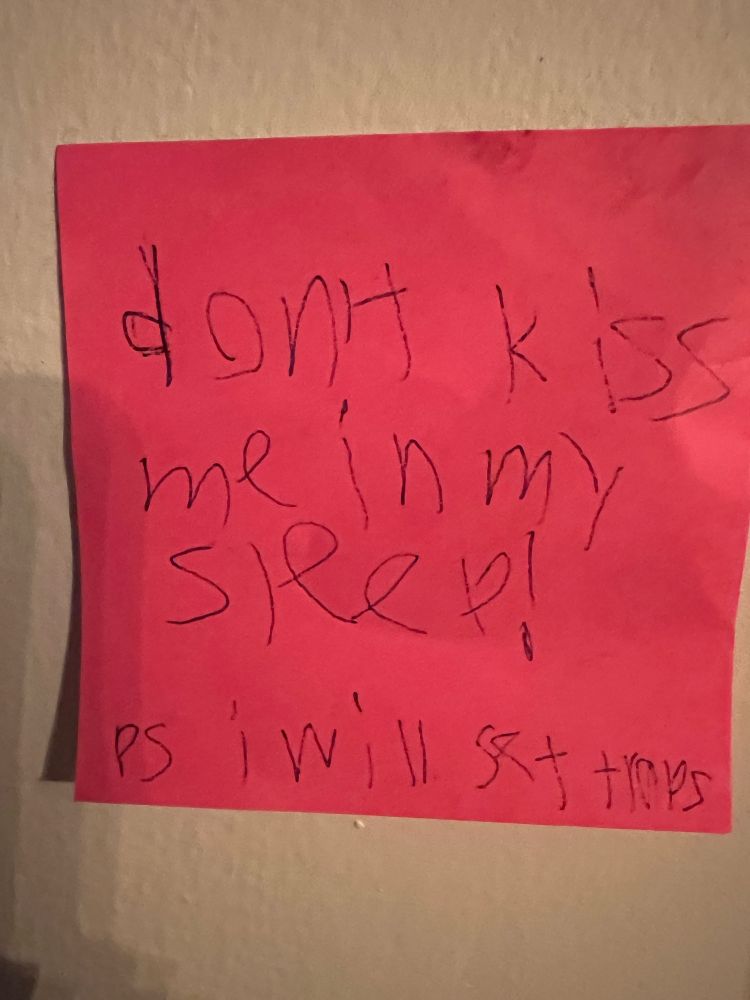 Red sticky note that says “don’t kiss me in my sleep! PS I will set traps”