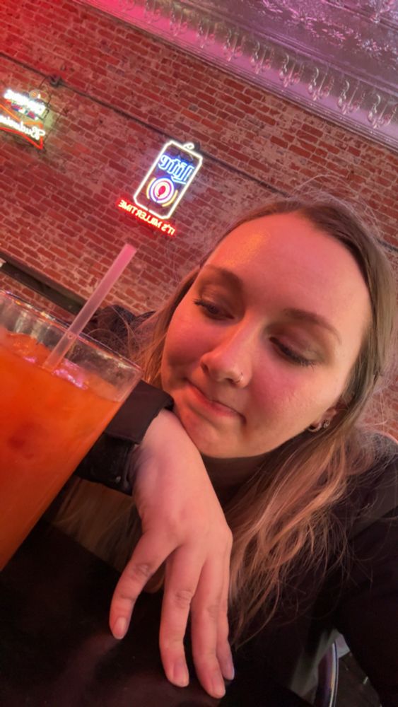 hailien staring at a bloody mary with some regret in her face. she’s a hot mess from partying all night. no sleep was had at this point 