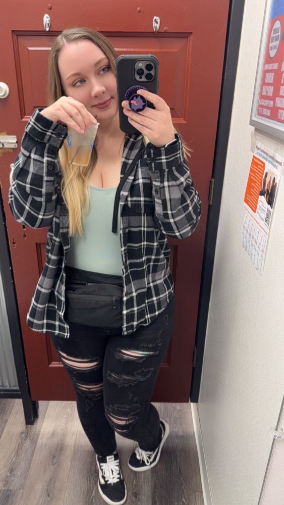 bar selfie of hailien holding a drink. she’s got ripped up black skinny jeans on and a black flannel. featuring a gengar popsocket