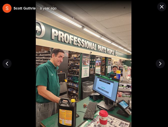 An employee behind the service desk of an O'reilly's Auto Shop gives a mean side eye to the photographer. The photographer's name, Scott Guthrie, is listed in the top left, followed by the words "a year ago" in reference to when the picture was taken. 