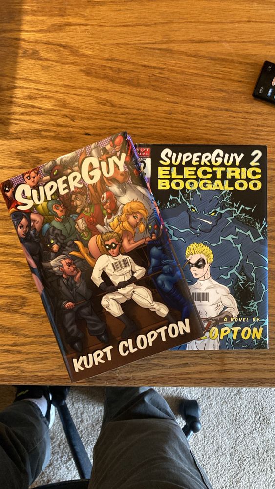 Photo of two books, titled SuperGuy and SuperGuy 2: Electric Boogaloo, by Kurt Clopton