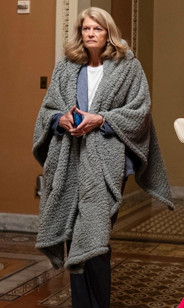 Lisa Murkowski, ghoul, wearing a grey hobo wrap she stole from an unhoused person because she really is that cruel and evil