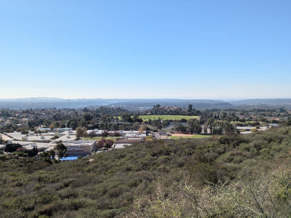 View looking west from a park in Rancho Penesquitos. Schools and residential neighborhoods in the near ground fade to valleys, a small rise, and eventually the ocean