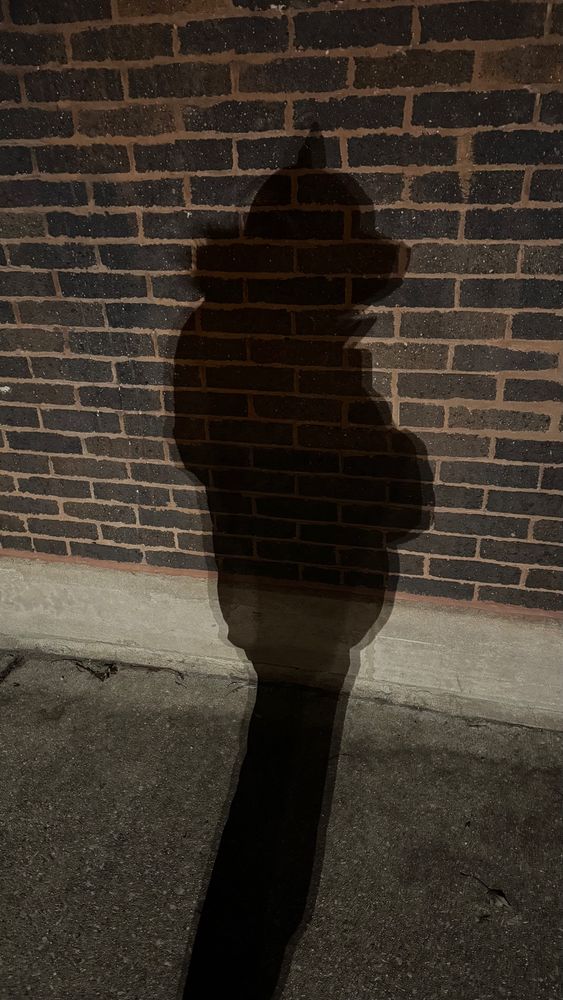 Shadow of a person wearing a pup hood and winter coat. 