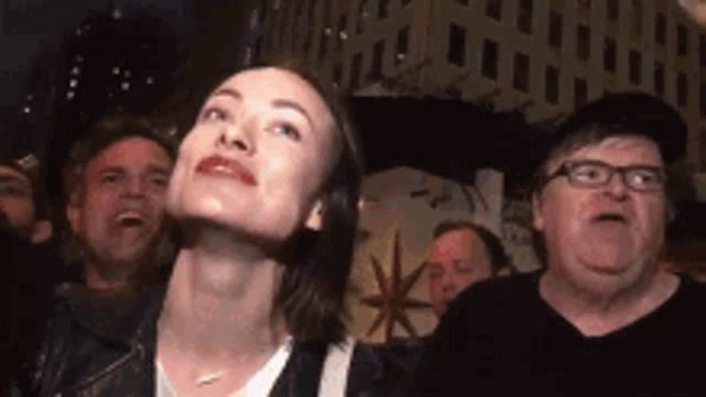 a woman is looking up at the sky while standing in a crowd .