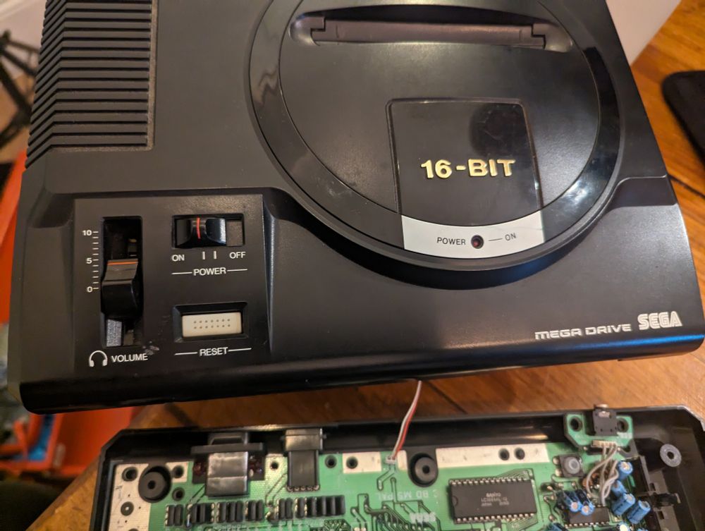 Sega megadrive in black with the top taken off exposing the circuit board beneath 