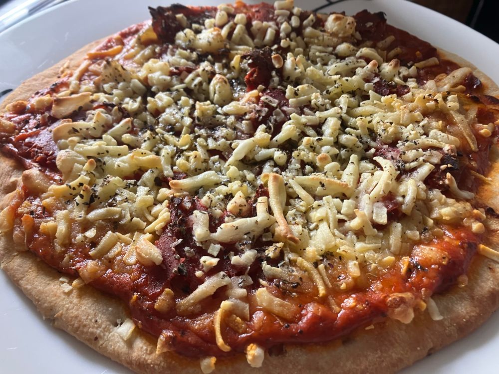 Vegan cheese and pastrami topped pizza with a pepper, garlic and a pesto sauce 