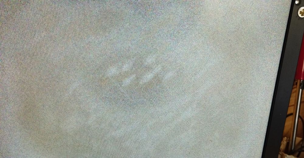 Monitor sem sinal apresentando uma mancha esbranquiçada que parece mofo por detrás da tela.