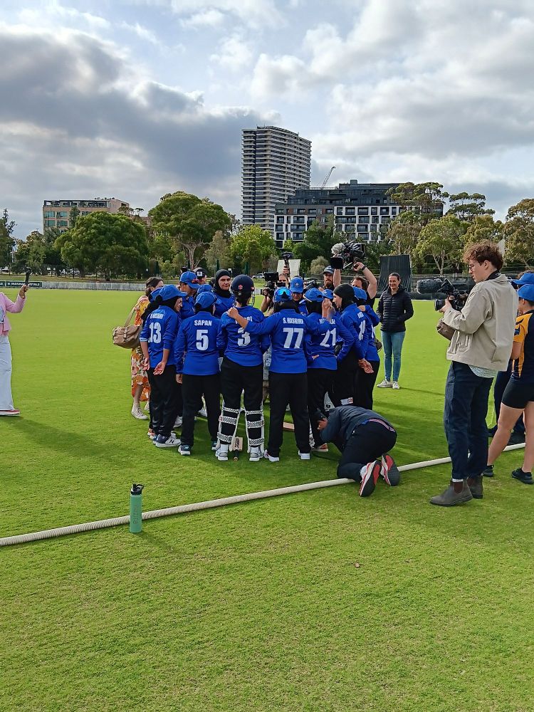 Afghanistan Women's Cricket Team, wearing blue shirts and black trousers, in a huddle before match