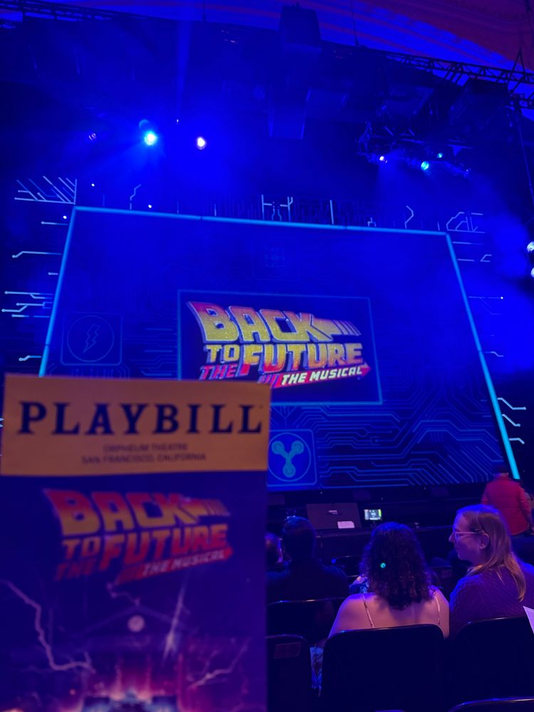 Playbill for “Back to the Future: The Musical” held up in front of the stage scrim mimicking the Playbill.