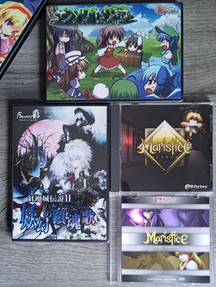 A photograph of multiple video games.
At the top, the case of the smash hit video game from 激辛 (Gekikara) Spice, Gensokyo no Nazo can be seen.
In the bottom left, Frontier Aja's high quality game; Koumajou Densetsu II (commonly known as Touhouvania 2 or Touhou 2 Castlevania 2) is also present.
To the right is the CD case of N-Factory's incredible isometric puzzle game Maristice along with its trial CD.