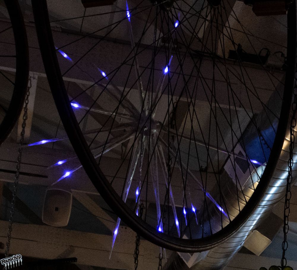 Starburst lamp seen through spokes of a bicycle wheel