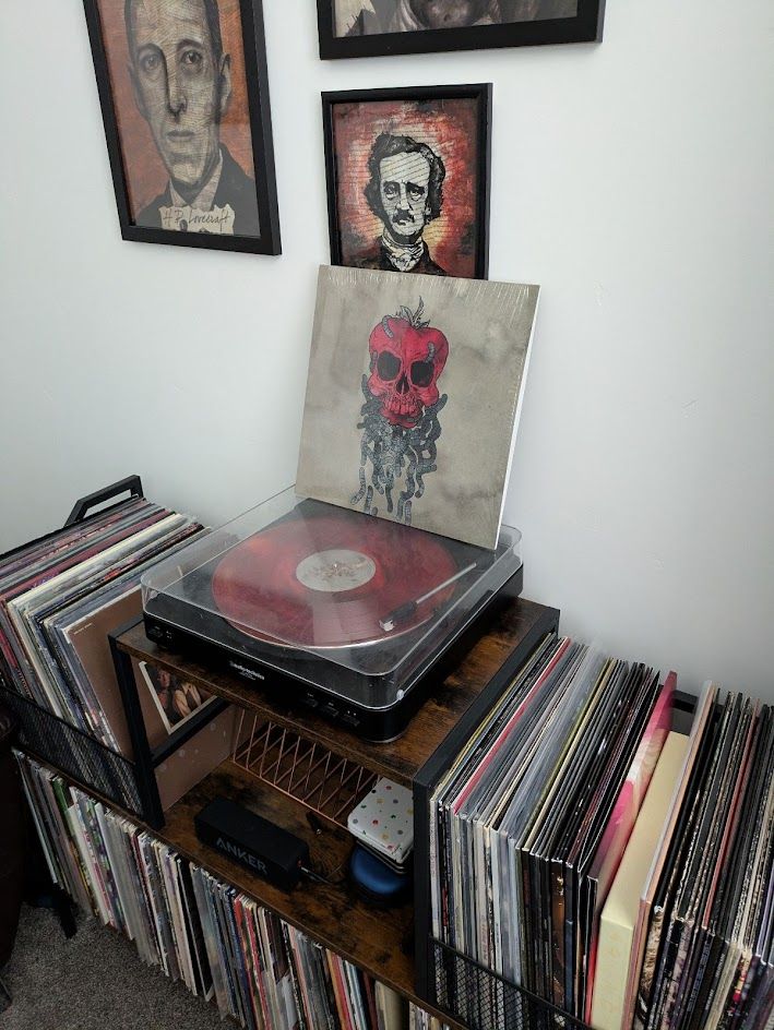 Dreamer vinyl cover sitting on turntable - red record playing - vinyl cabinet. Horror author pictures on the wall (lovecraft, poe).