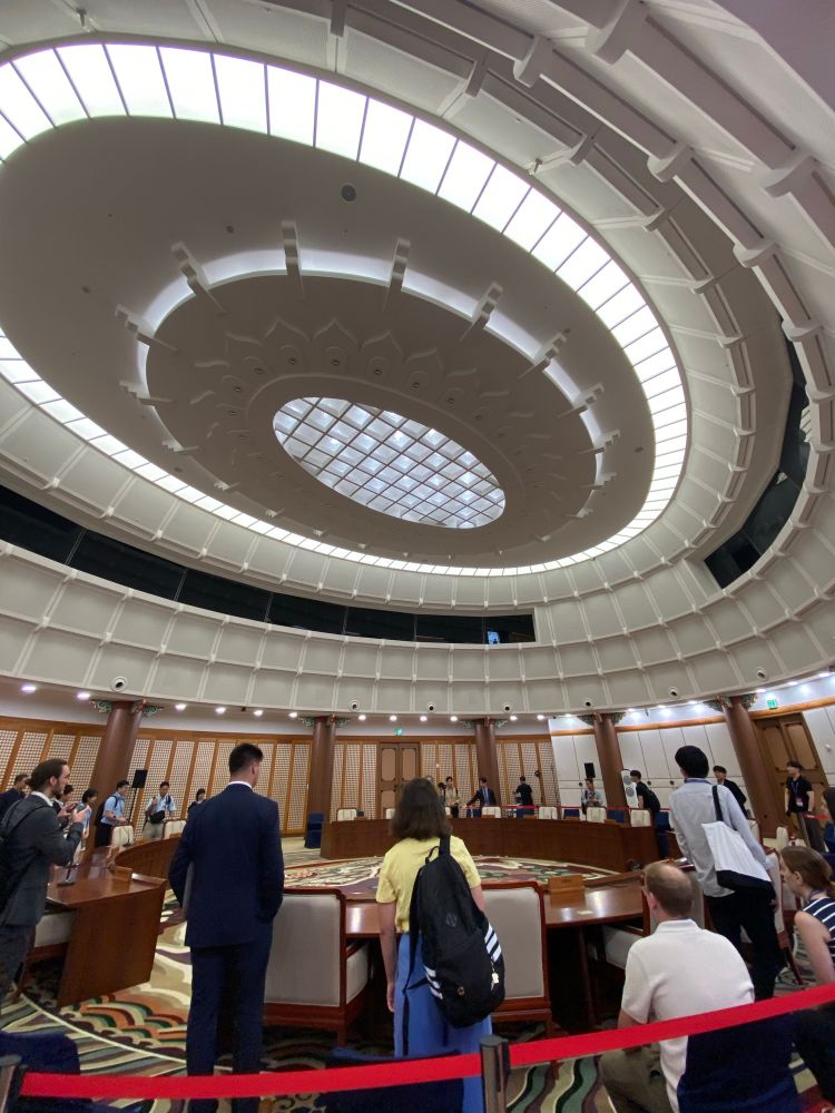 Brightly lit roof over negotiators sitting and standing in the rotunda  