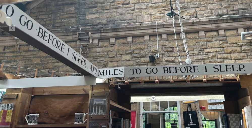 Interior of a bookshop with fragments of poems hung on boards. The ones visible here are 'to go before I sleep and miles to go before I sleep'