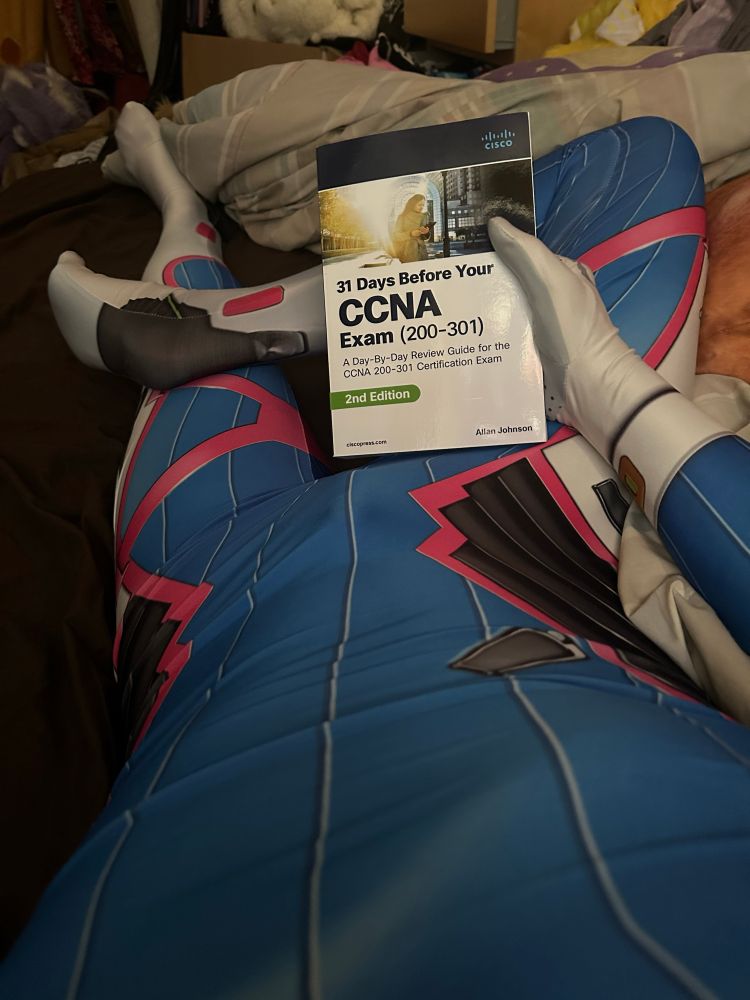 I’m wearing a D.Va zentai, a character from Overwatch. Photo is my POV lying in bed holding a paperback textbook “31 Days Before Your CCNA Exam”