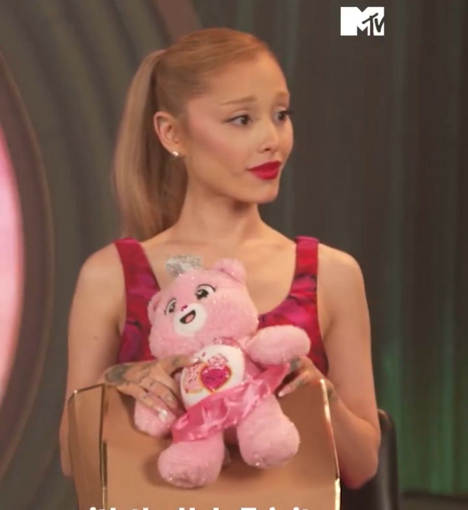 Ariana sitting for interview with a Glinda care bear she was gifted 