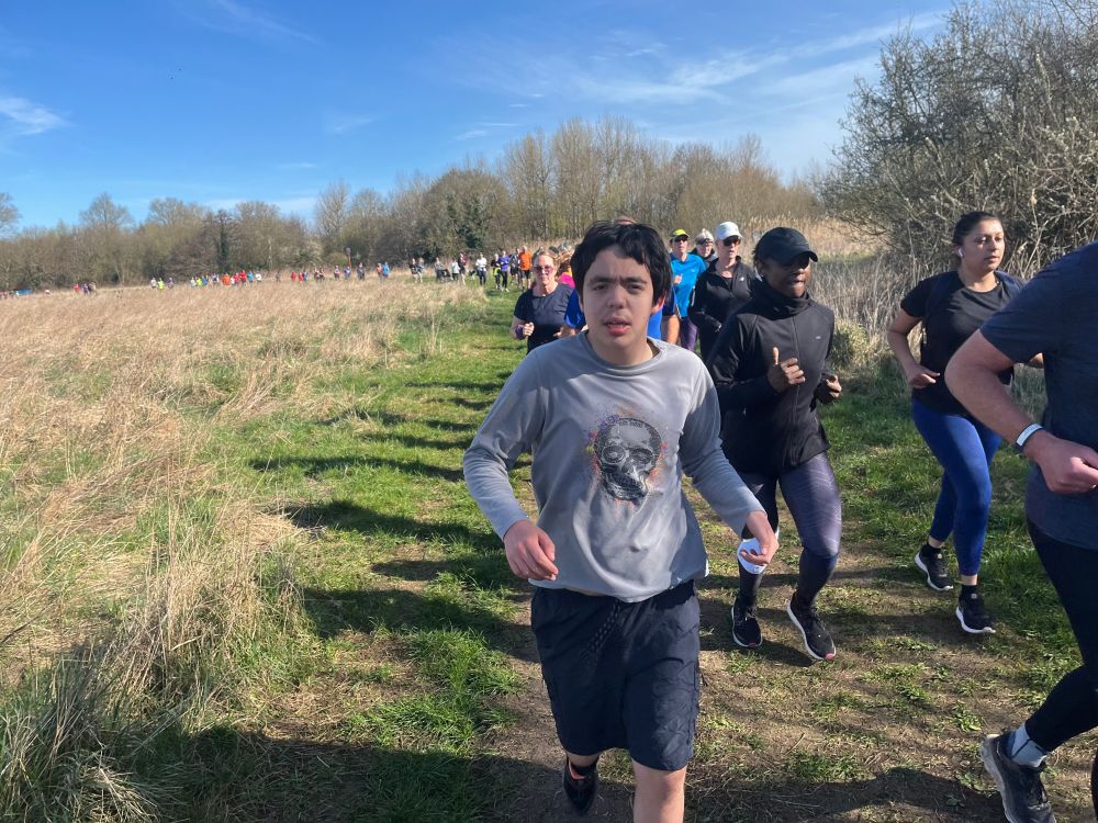 Joe running in a parkrun event in a field next to the Thames in Abingdon